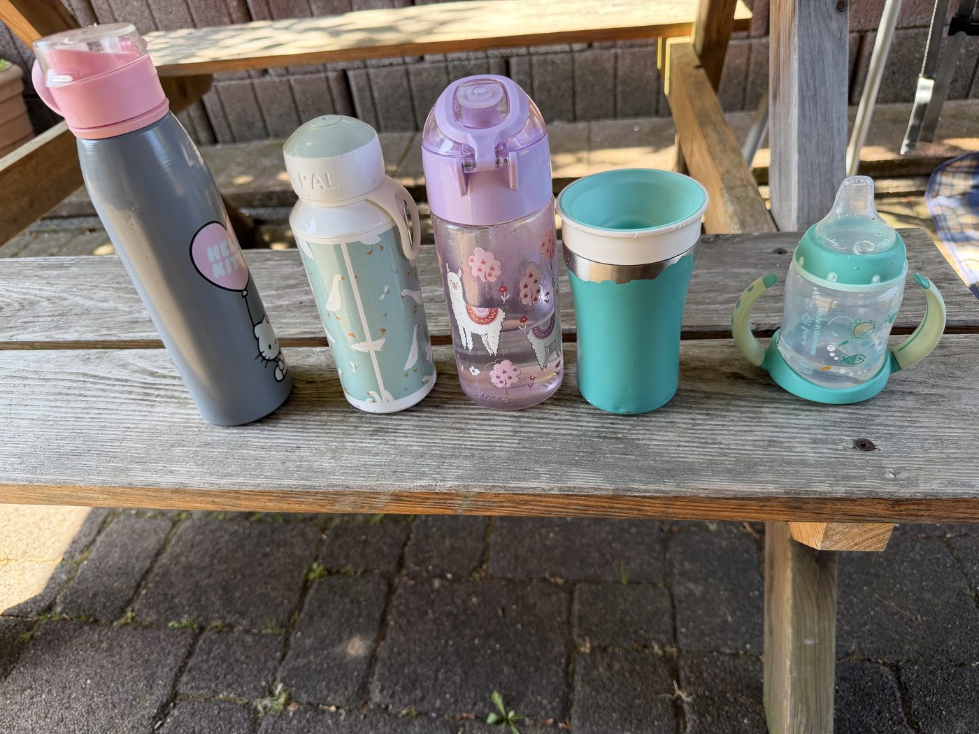 Bunte Trinkflaschen der Kinder auf der Bank